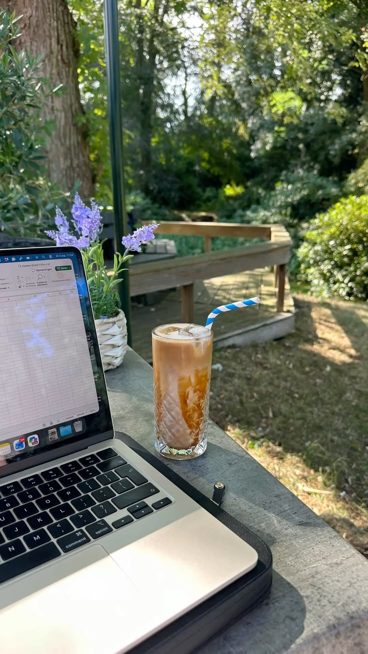 Iced coffee beside a laptop in the garden